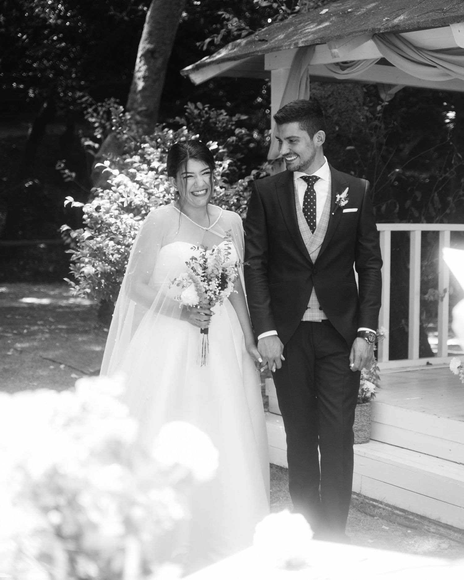 Black and white wedding photos showing a couple walking together in an outdoor garden setting.