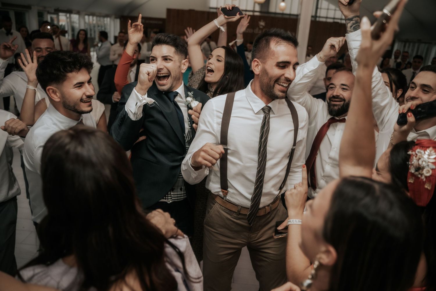 Wedding guests dance and celebrate joyfully at a lively reception party.