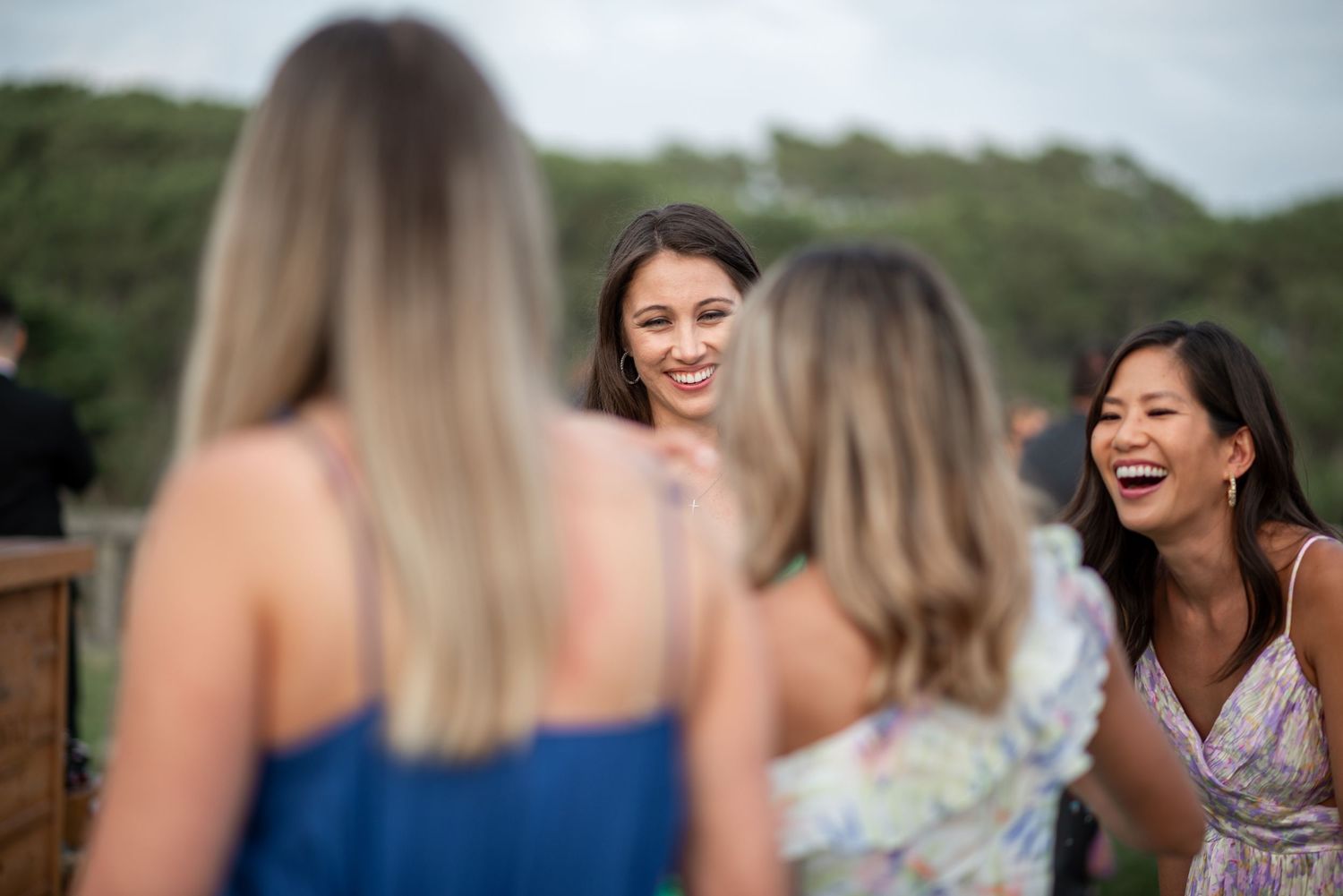 Guests laughing and socializing at an outdoor wedding reception with colorful dresses.