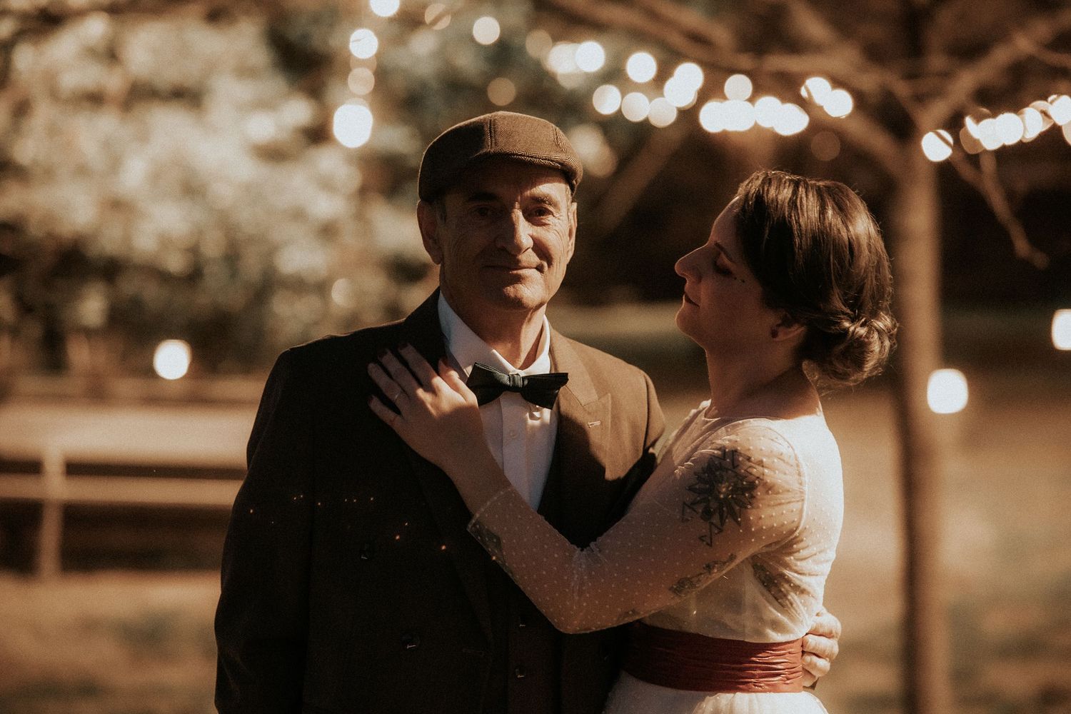 A couple shares an intimate dance moment during a wedding reception with warm sepia lighting and bokeh effects.