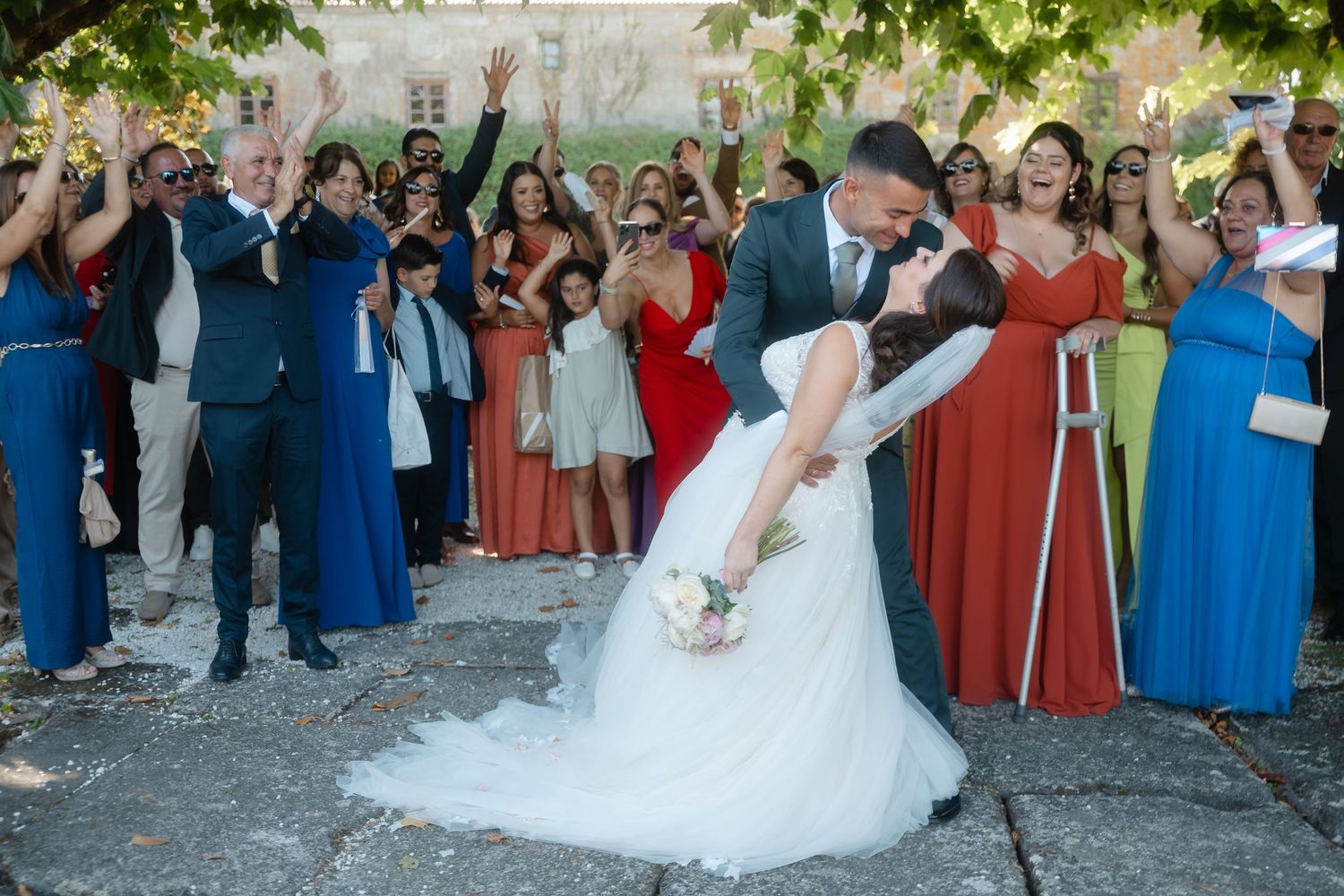Wedding guests form a circle around dancing newlyweds during outdoor reception celebration.