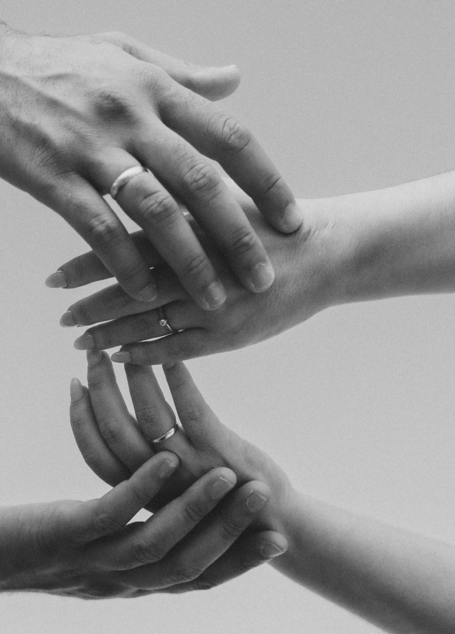 Black and white close-up photos of hands with wedding rings in various artistic poses.