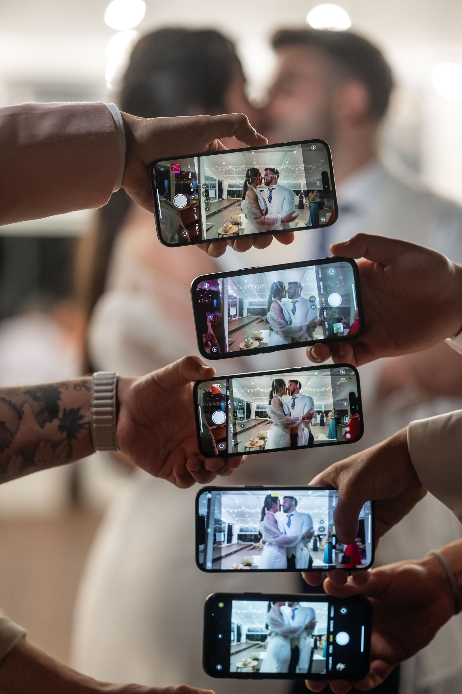 Multiple smartphones held side by side displaying synchronized video content on their screens in a bright indoor setting.