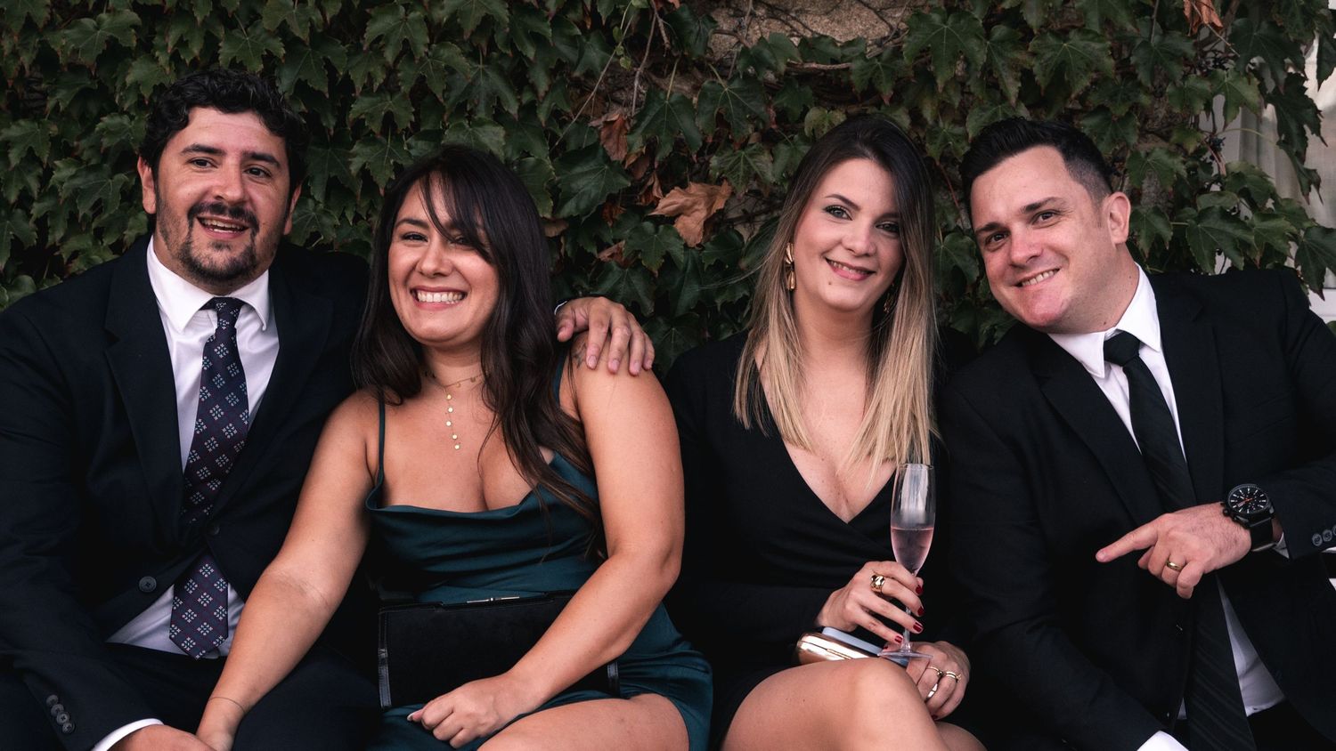 Joyful group poses together outdoors in formal attire at a celebratory gathering.