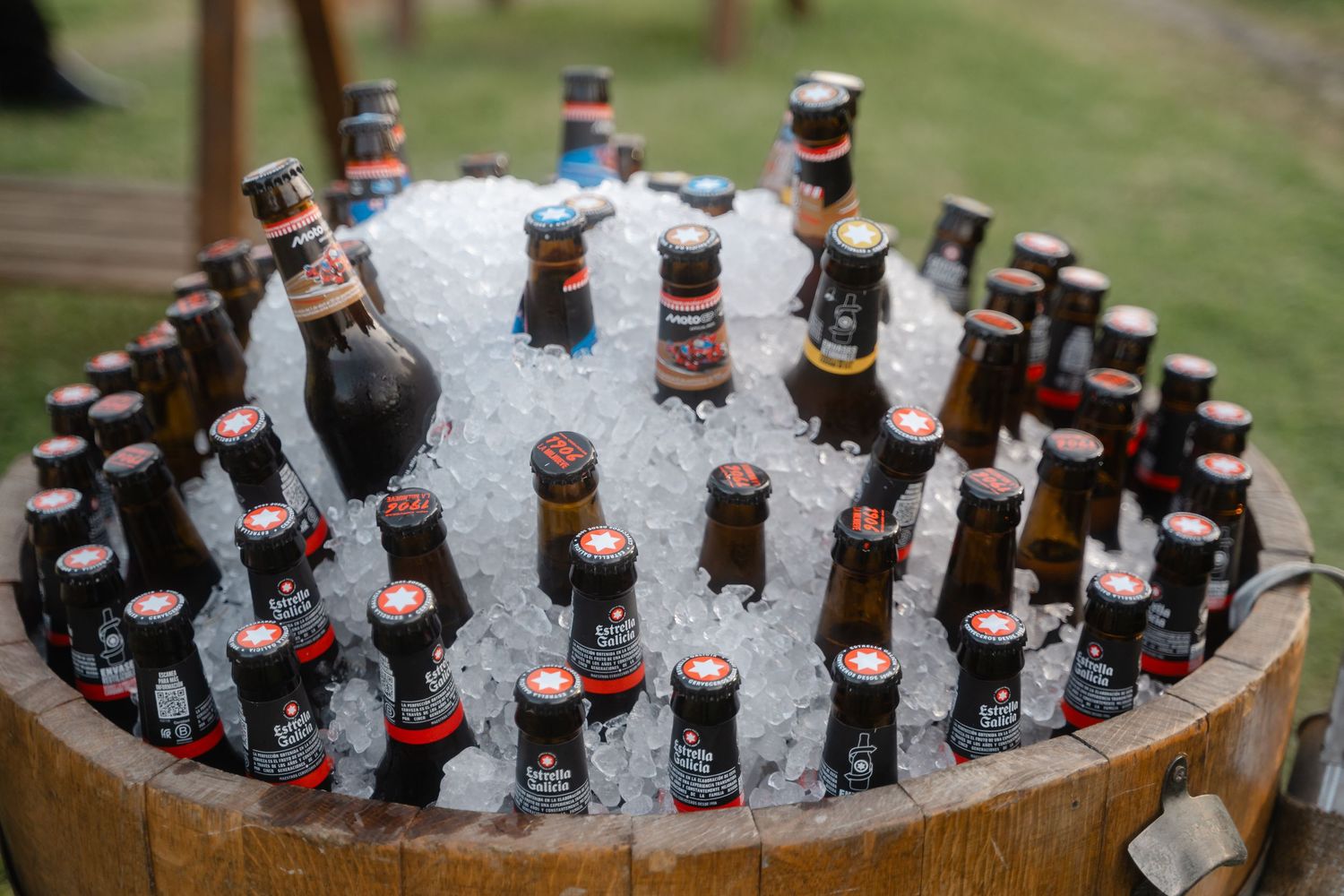 Glass bottles of beer chilling in ice at an outdoor party.