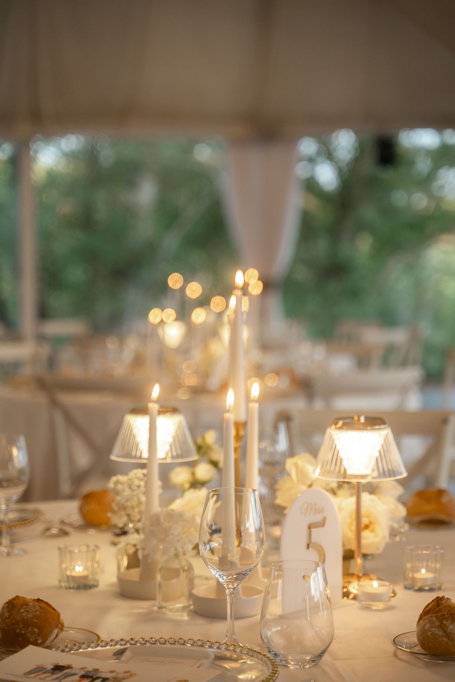Elegant wedding reception table setting with glowing candles and glassware creating a romantic ambiance.
