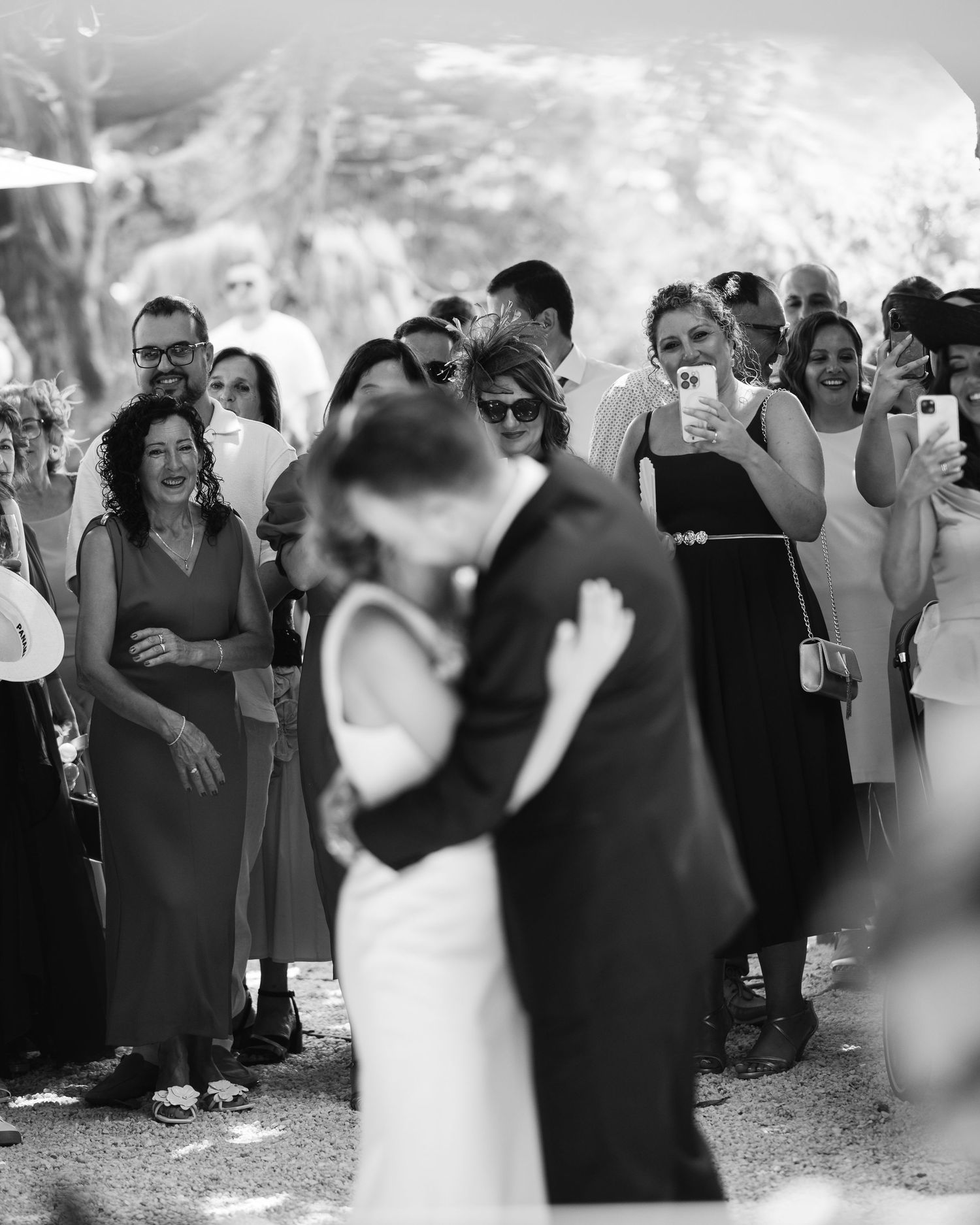 Wedding guests gather around to watch a romantic first dance between newlyweds at an outdoor reception.