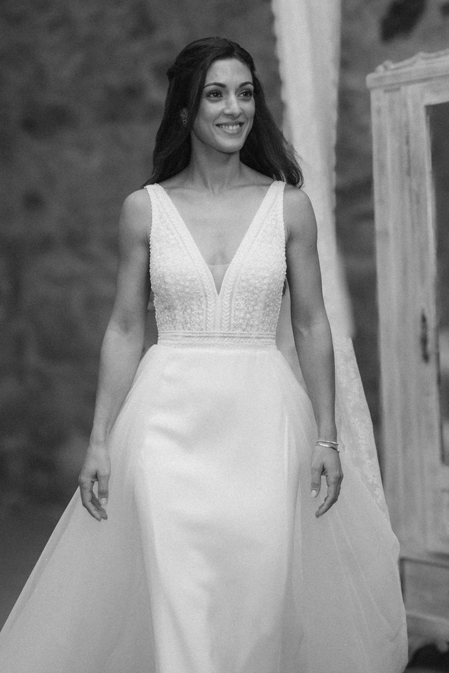 A sequence of black and white photos showing details of an elegant white wedding dress with lace details.