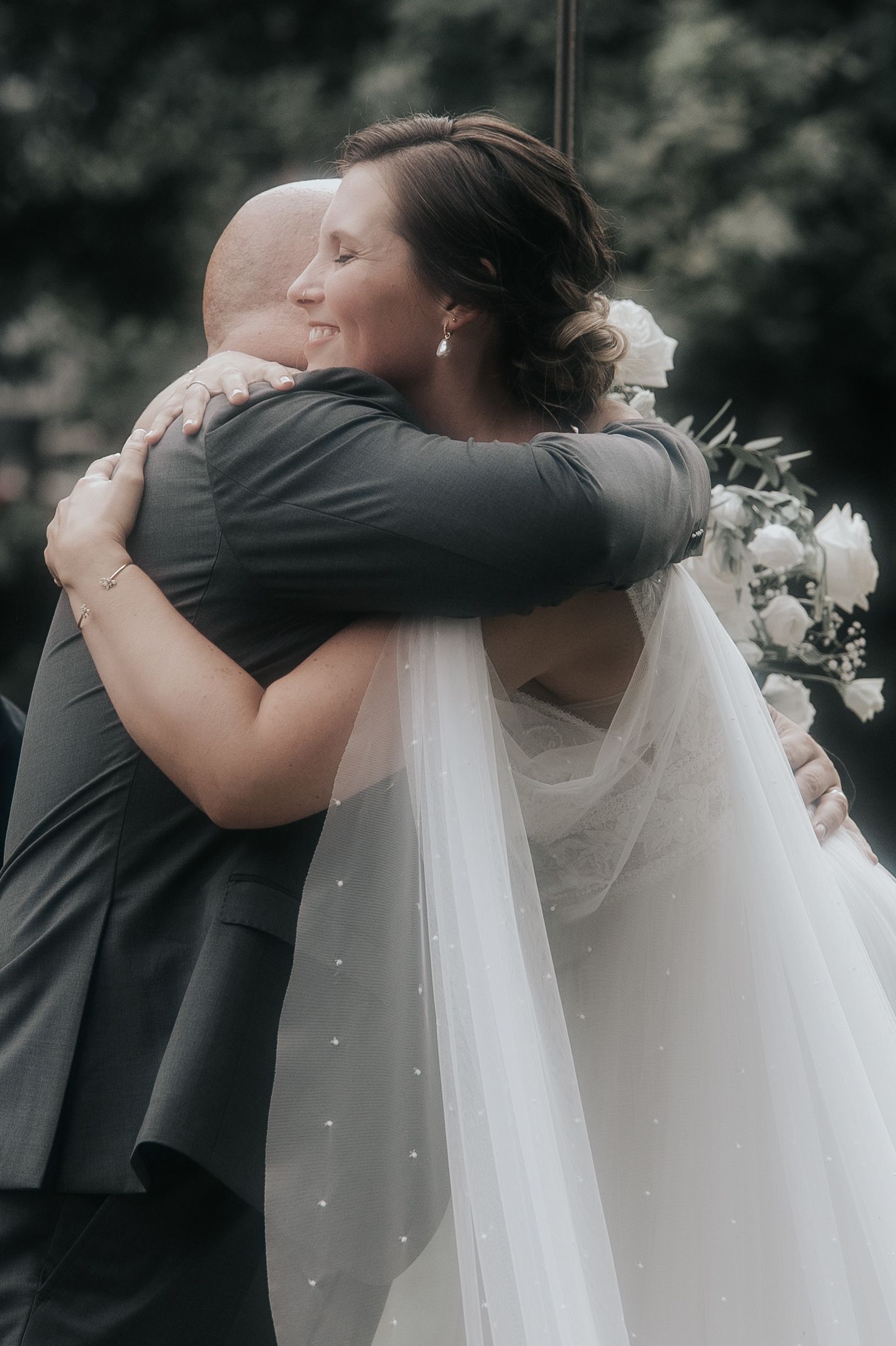 Series of intimate wedding moments showing a couple hugging beneath white floral decorations.