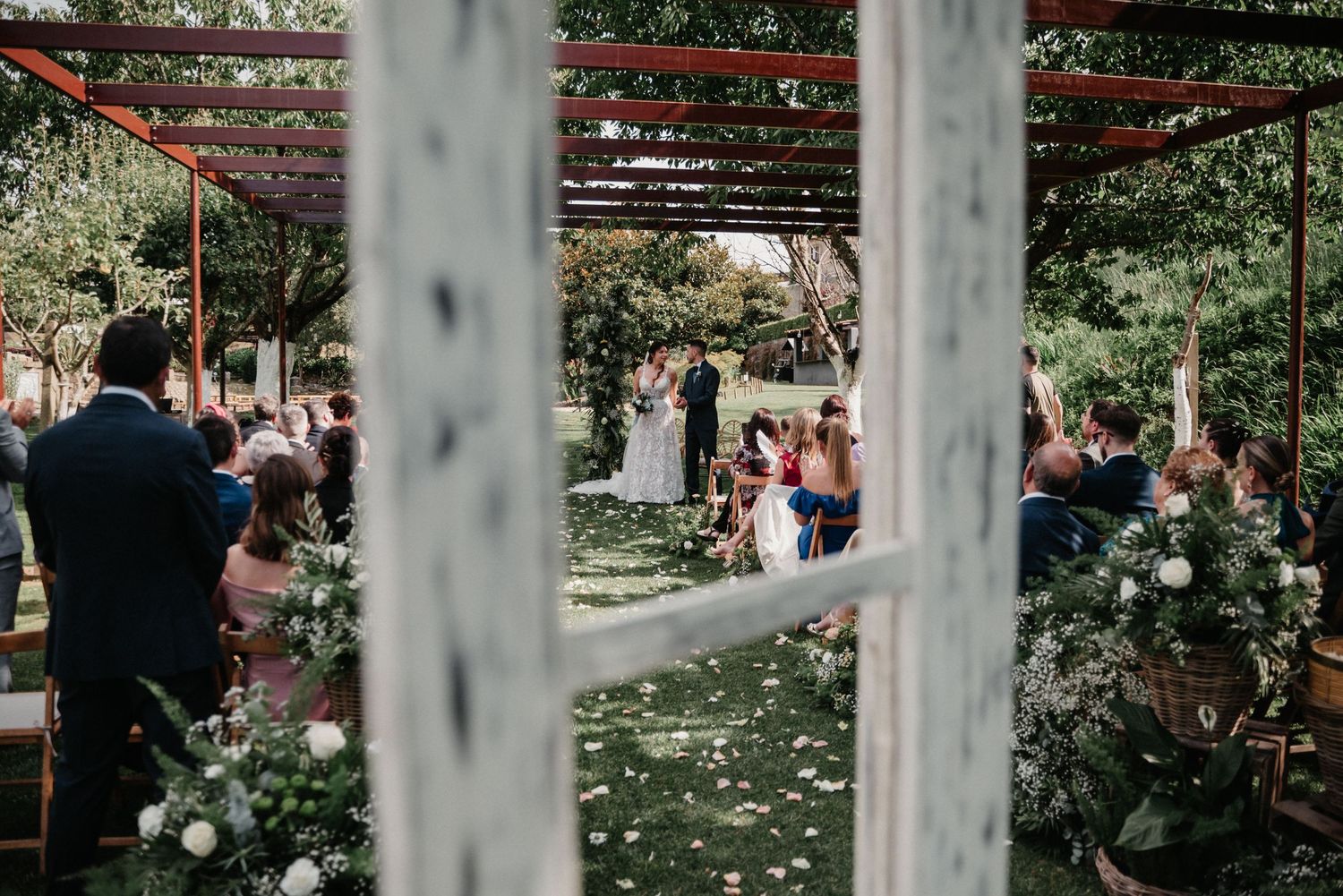 Outdoor wedding venue decorated with string lights and white floral arrangements.