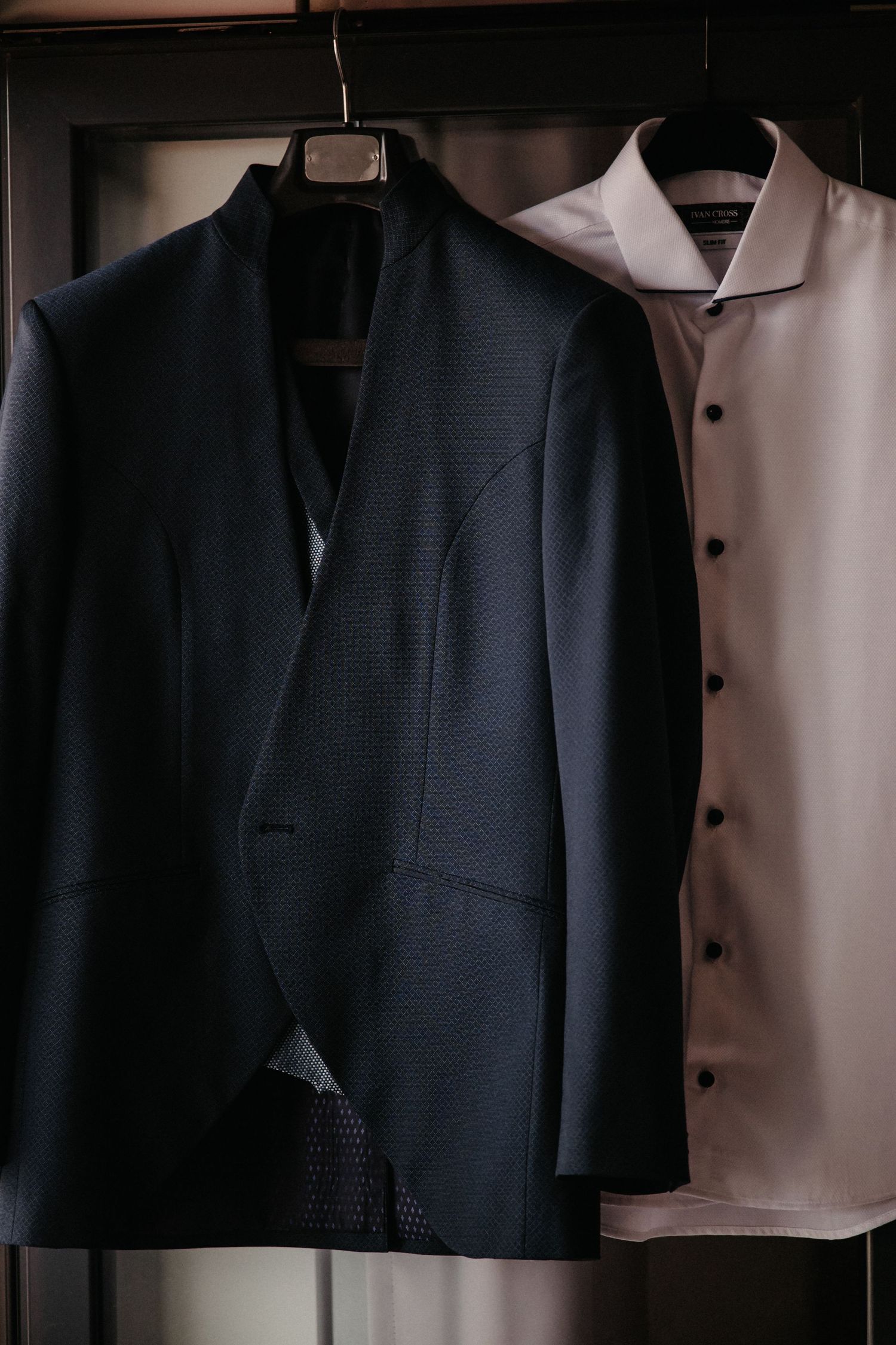 A row of dark formal suit jackets and blazers hanging on a clothing rack in a store or closet.