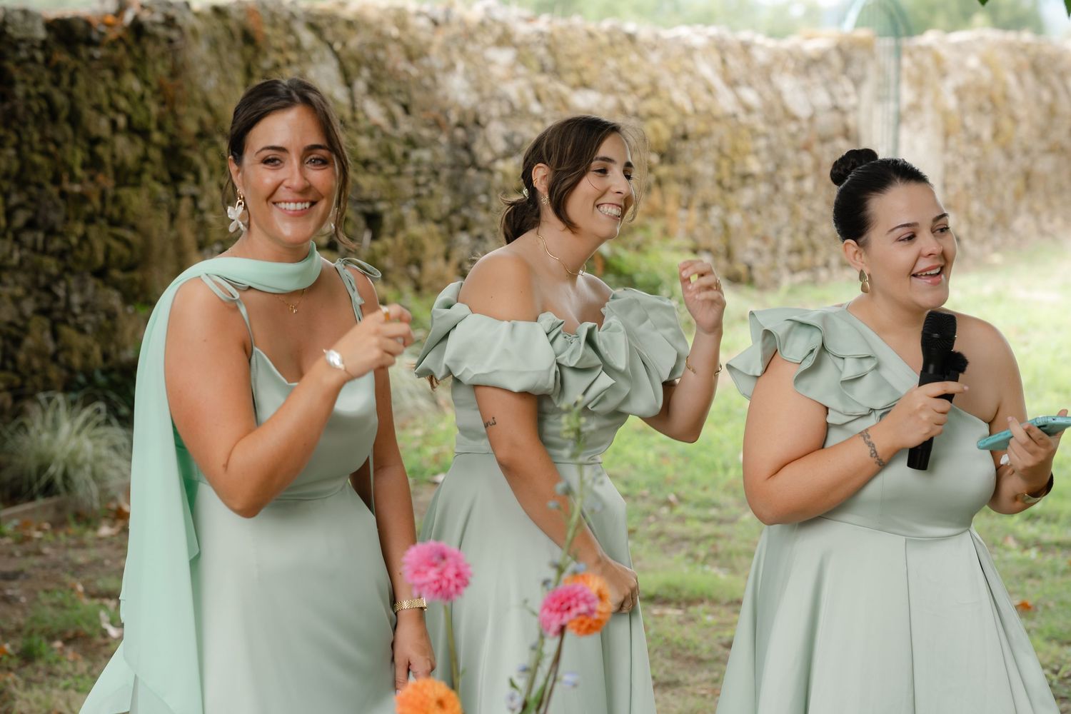 Bridesmaids in mint green dresses laugh and smile together during outdoor wedding photo session.