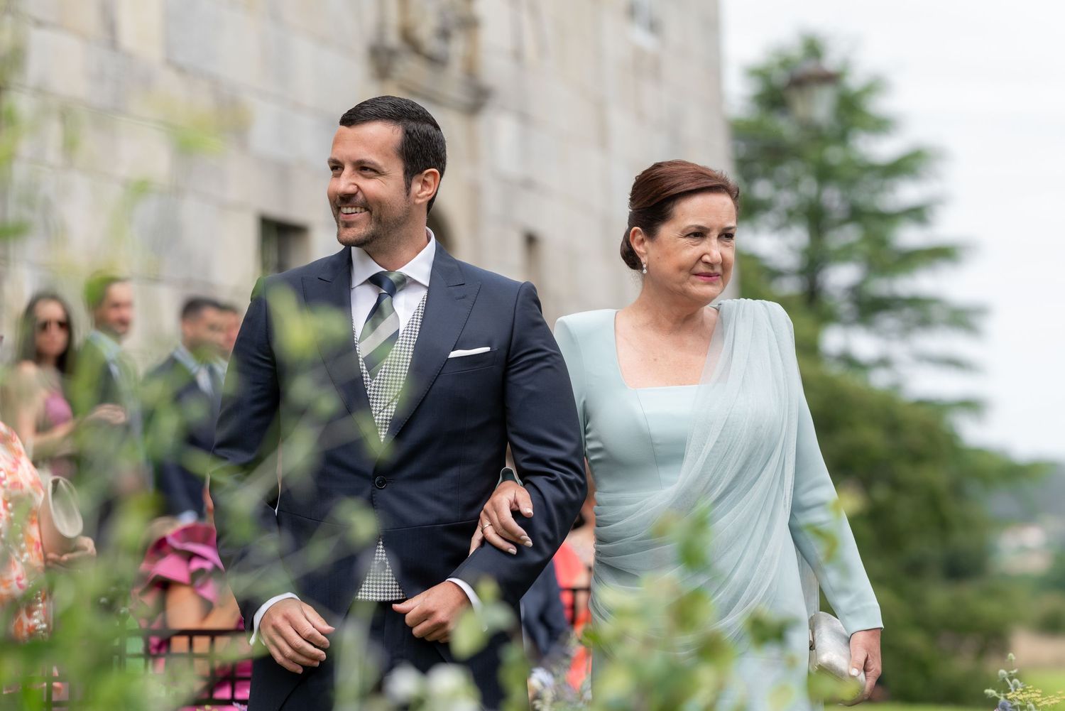 Wedding guests celebrate joyfully outdoors during a sunny garden ceremony.