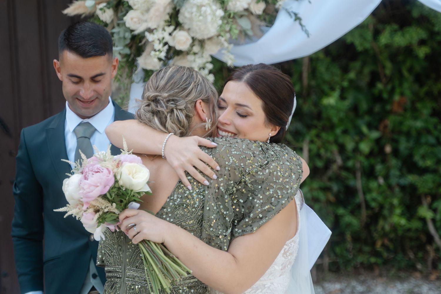 Wedding guests share warm embraces and joyful moments during an outdoor celebration.