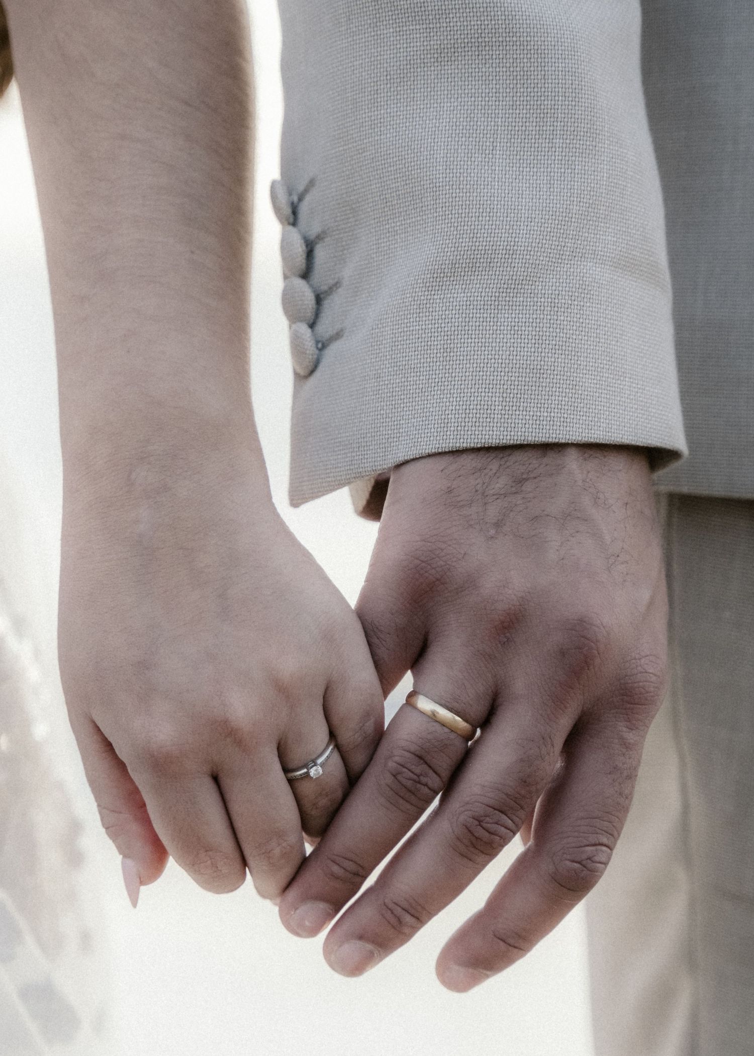 Close-up shots of newlyweds' hands wearing wedding rings, showing their interlocked fingers.
