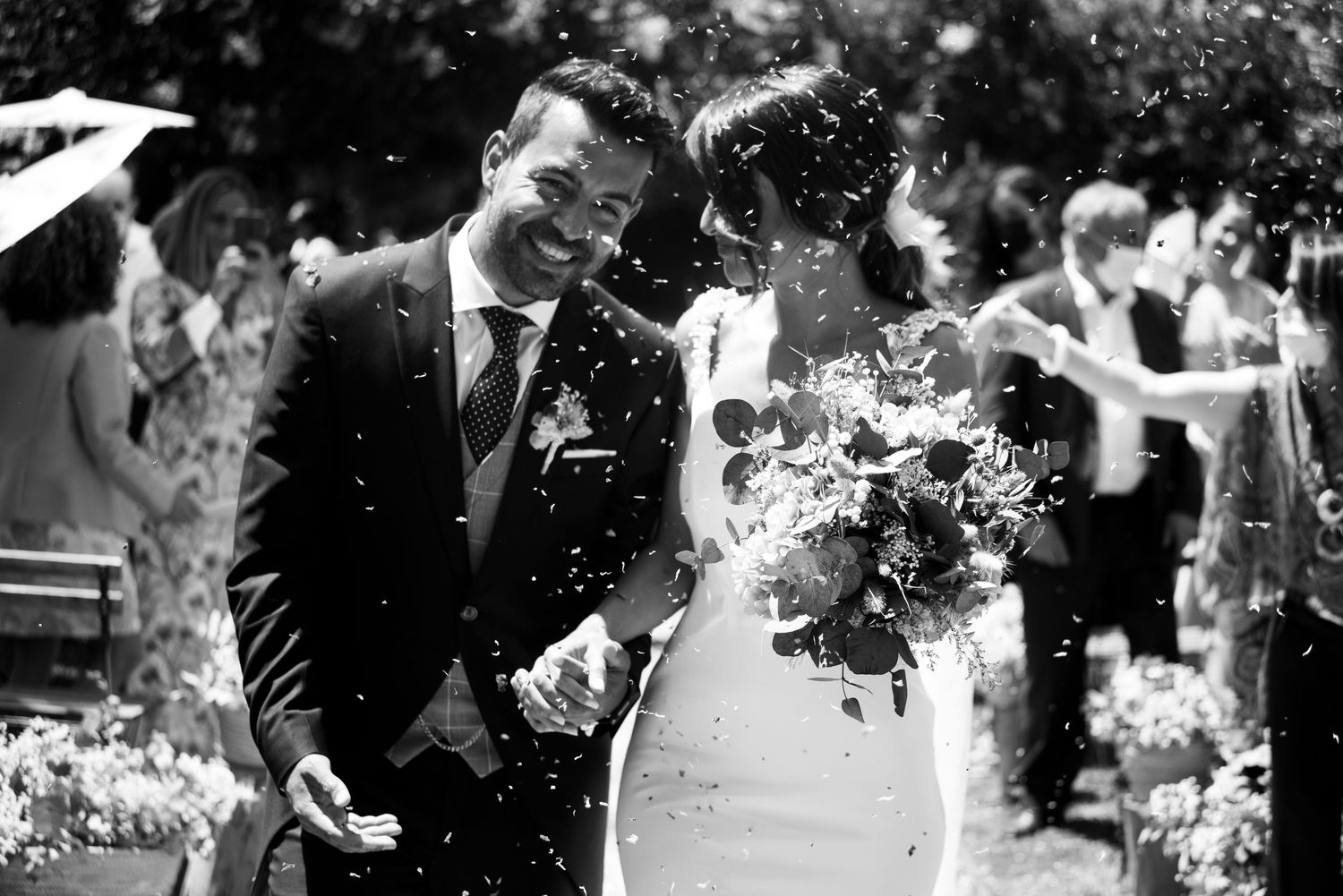 Black and white photo of wedding guests throwing confetti at a celebration.