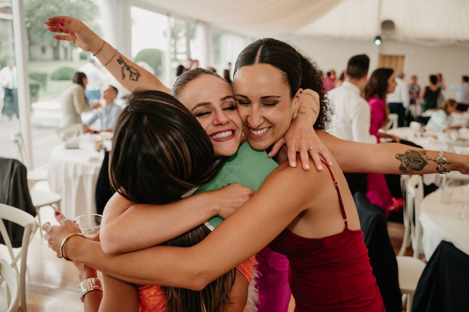 People embrace and share joyful hugs during a celebratory event in a bright indoor venue.