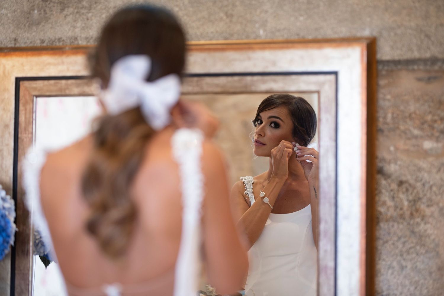A group of people getting ready in front of mirrors in an elegant dressing room with stone walls.