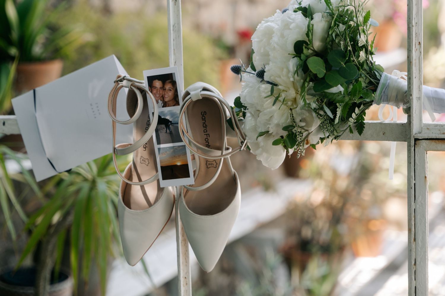 White ceramic planters and decorative items hanging from strings against a bright window with greenery.
