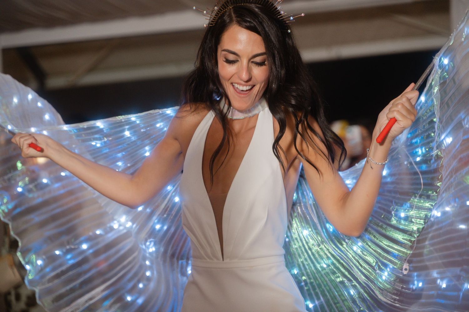 Dancers with glowing LED wings creating magical light effects during a wedding reception performance.