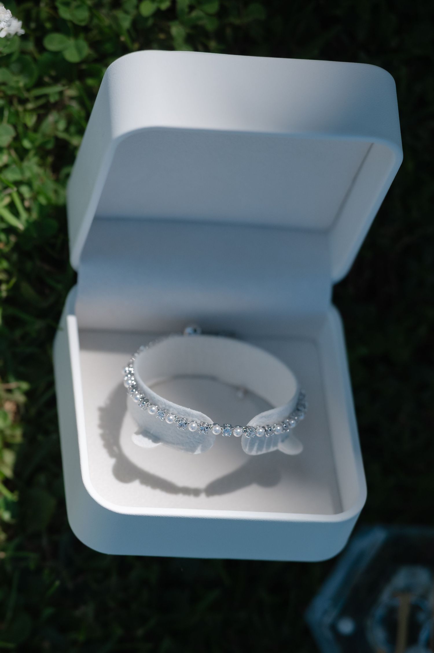A series of white jewelry boxes displaying delicate silver necklaces with crystal embellishments against a dark background.