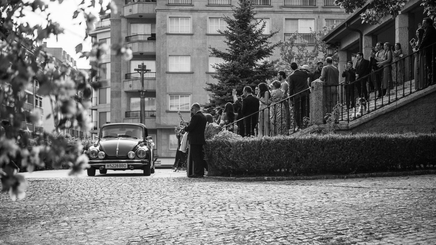 A black and white panoramic montage of urban street scenes showing buildings and vintage cars.