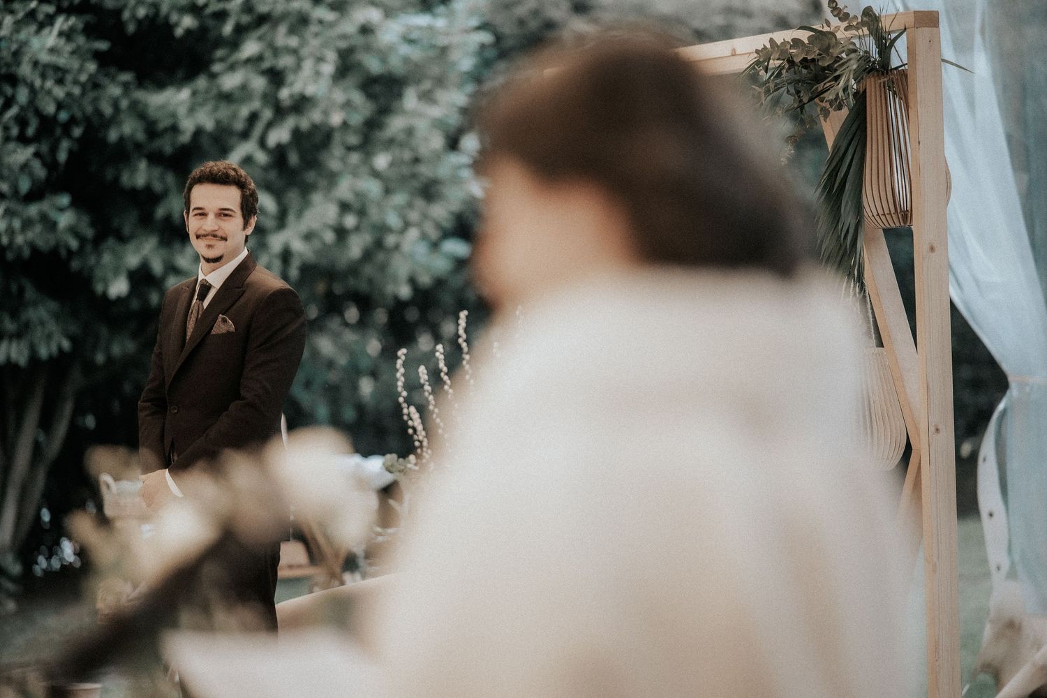 Intimate outdoor wedding ceremony moment captured through blurred foliage.