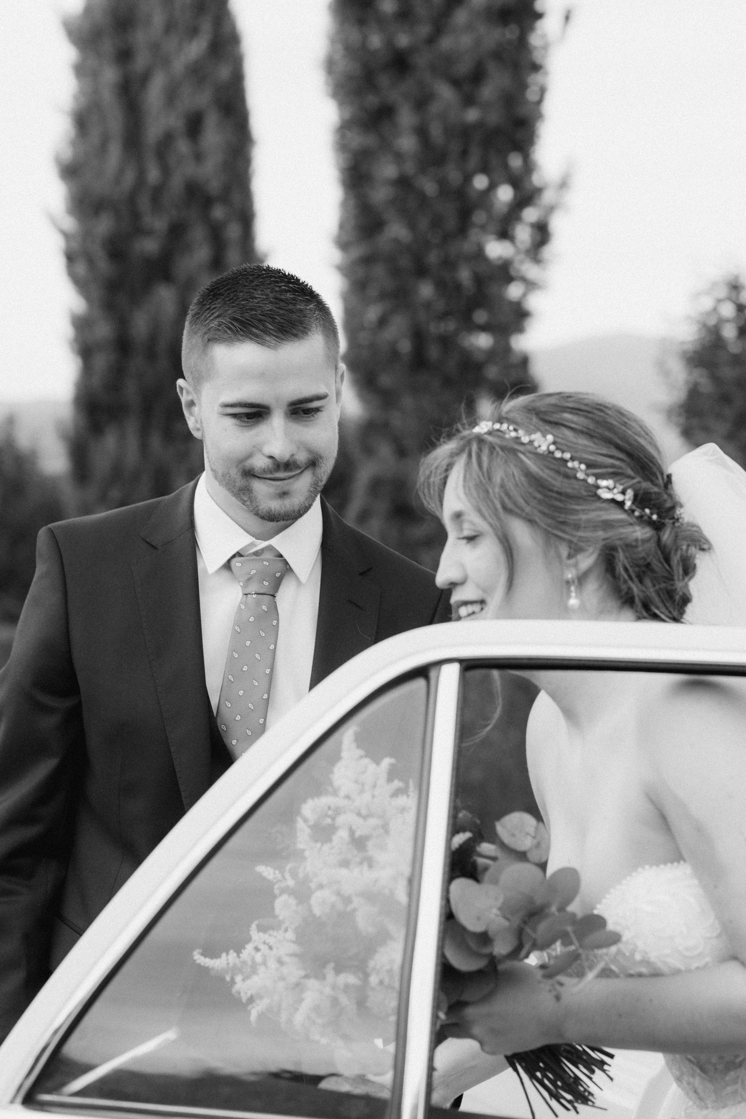 A series of black and white wedding photos showing a couple entering a car with cypress trees in the background.