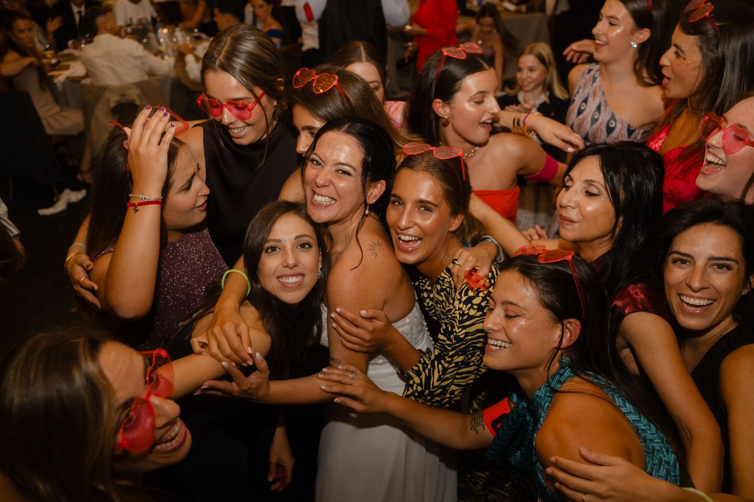 A crowded nightclub dance floor filled with people laughing and dancing together in a dimly lit space.
