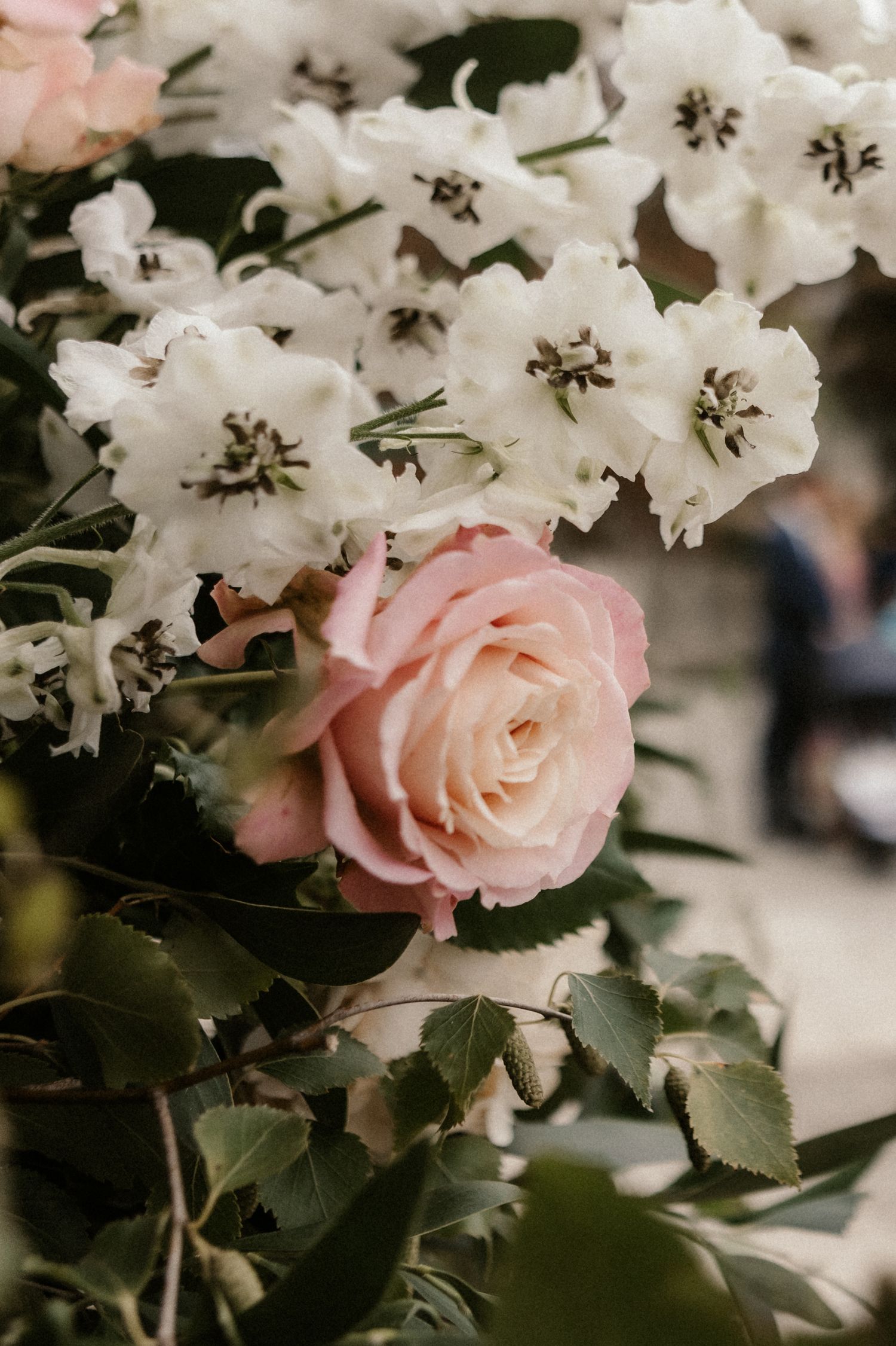 Delicate pink roses and white flowers create a romantic floral arrangement with soft, muted tones.