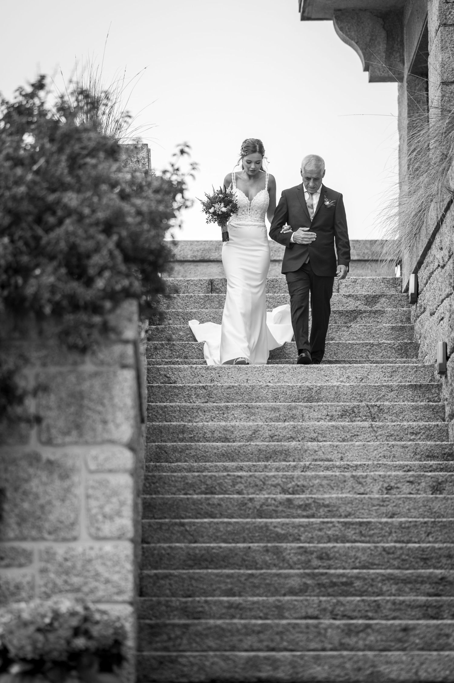 A series of black and white photos showing a couple descending stone steps in formal wedding attire.