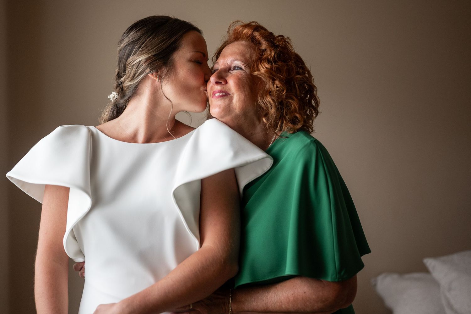 Two people in white and green attire share an intimate moment against a neutral background.
