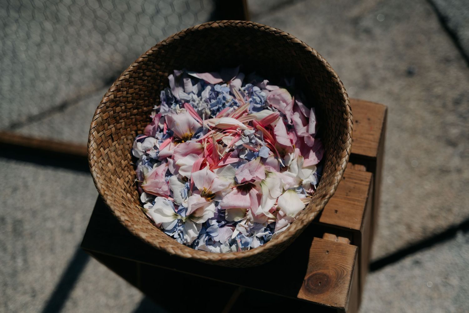 Confetti and flower petals arranged in rustic baskets and bowls on a wooden table.