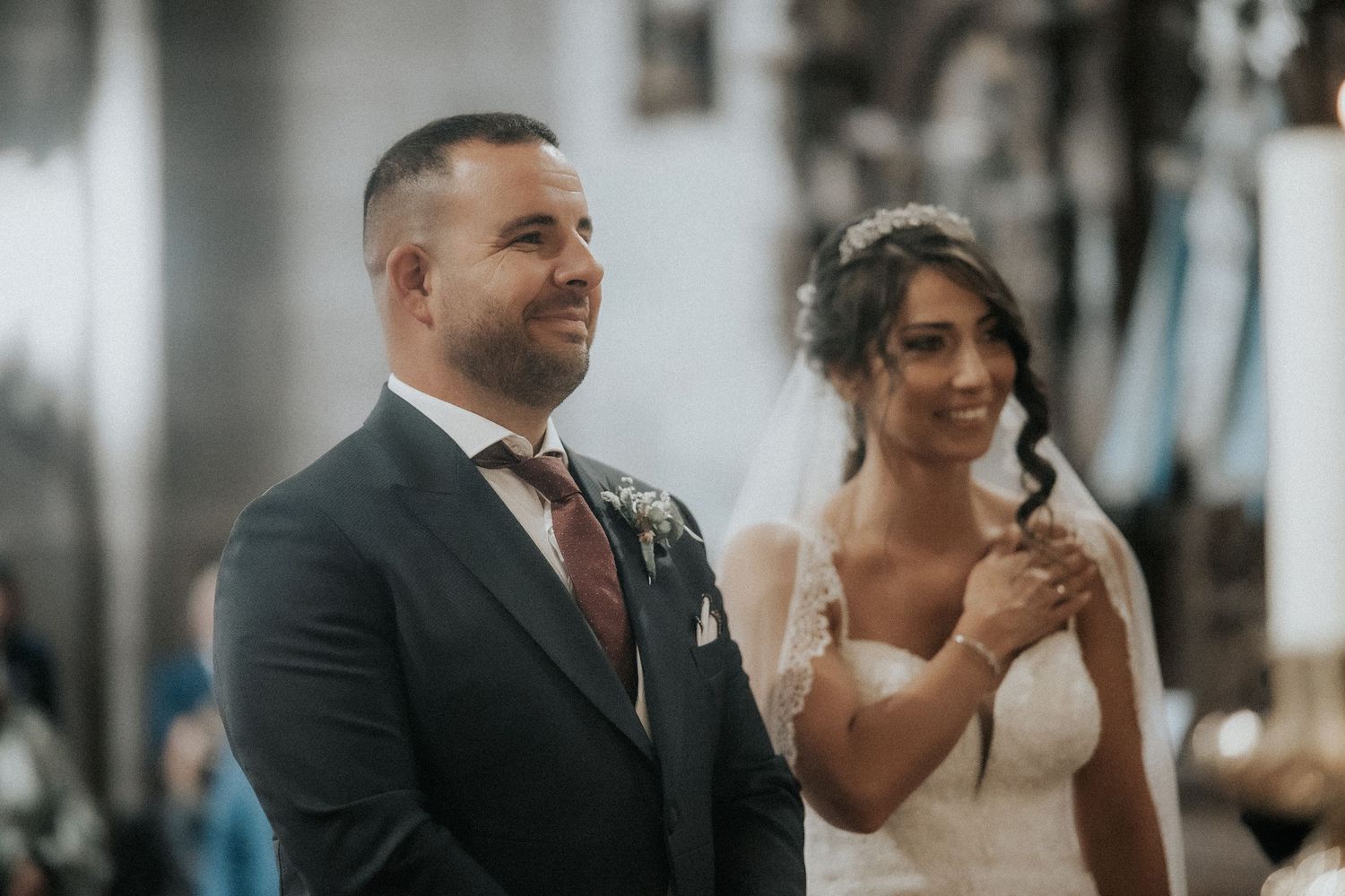 A joyful couple shares an emotional moment during their wedding ceremony in a beautifully lit indoor venue.