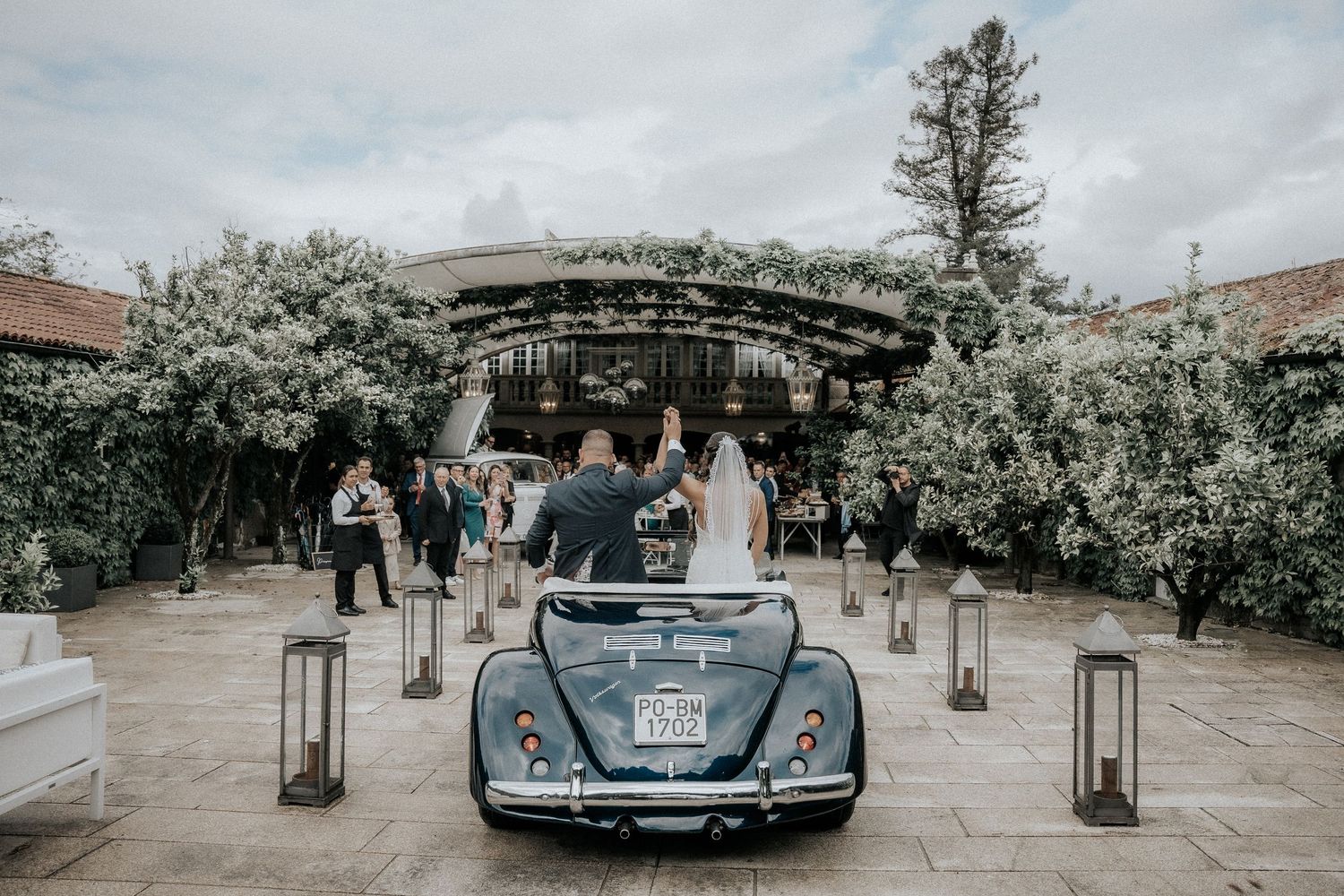 A vintage car decorated with lanterns and floral arrangements at an outdoor wedding ceremony venue.