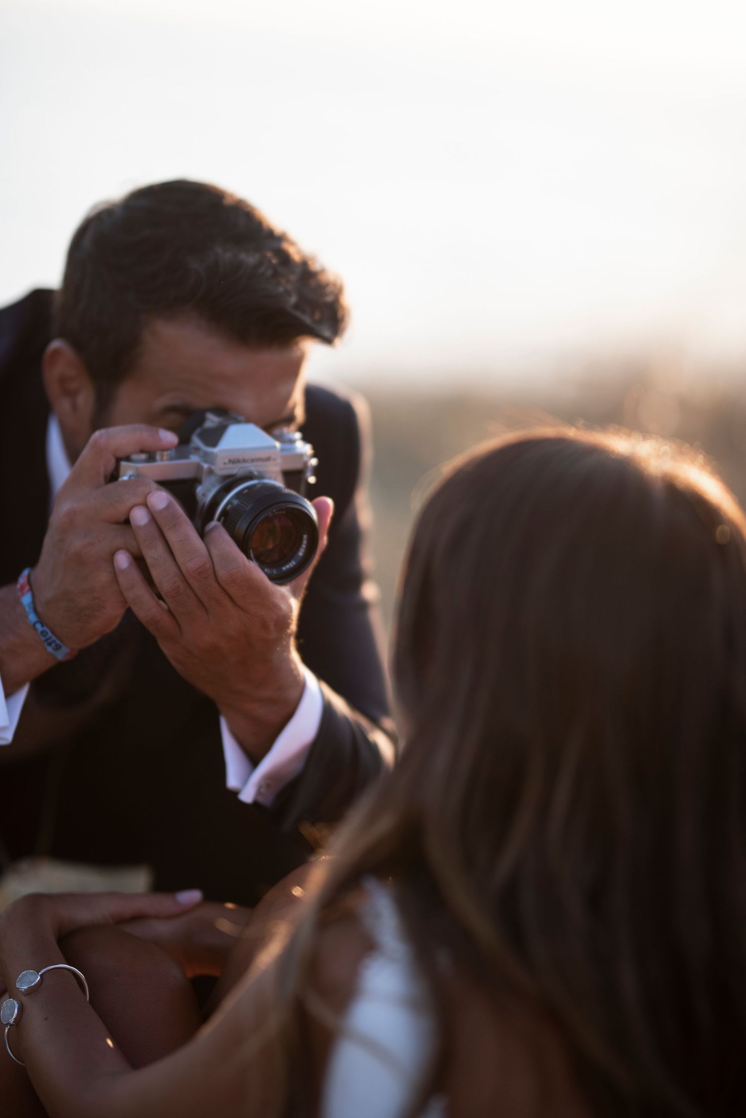A photographer captures moments during a sunset beach photoshoot.