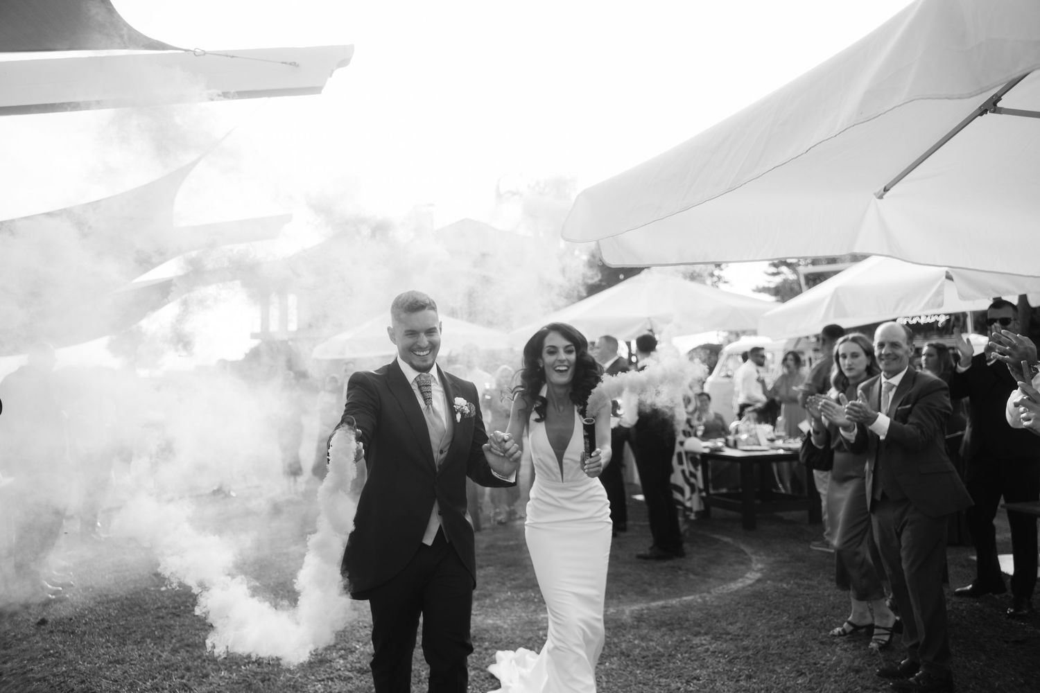 A black and white photo showing a large group of wedding guests gathered outdoors under a tent.