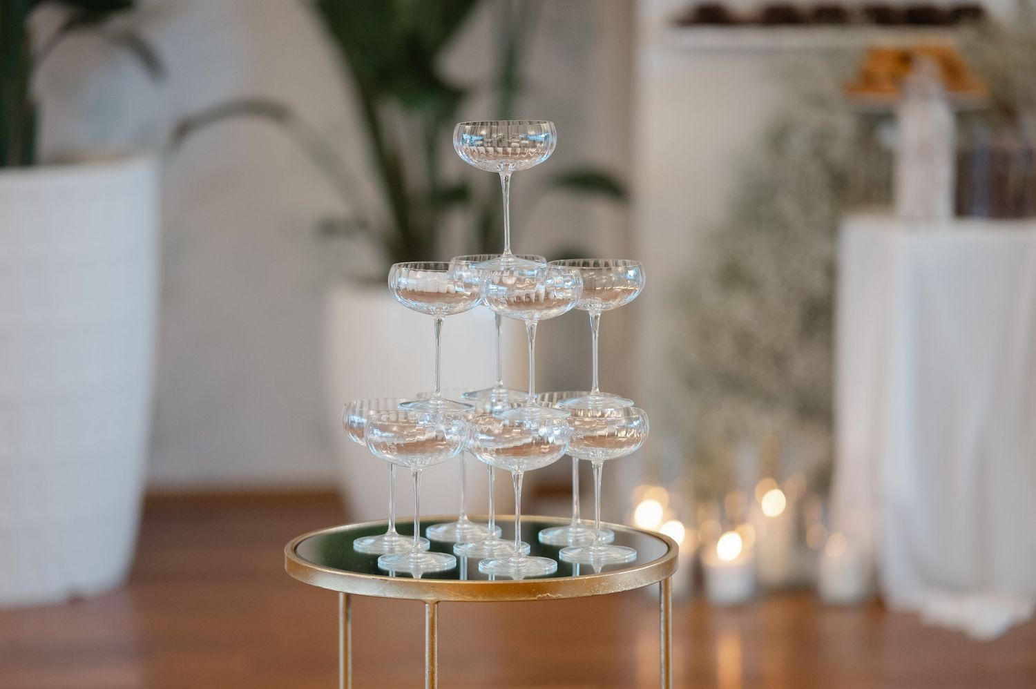 Elegant tiered glass cake stand with crystal-like details displayed at an indoor event with soft candlelight in background.