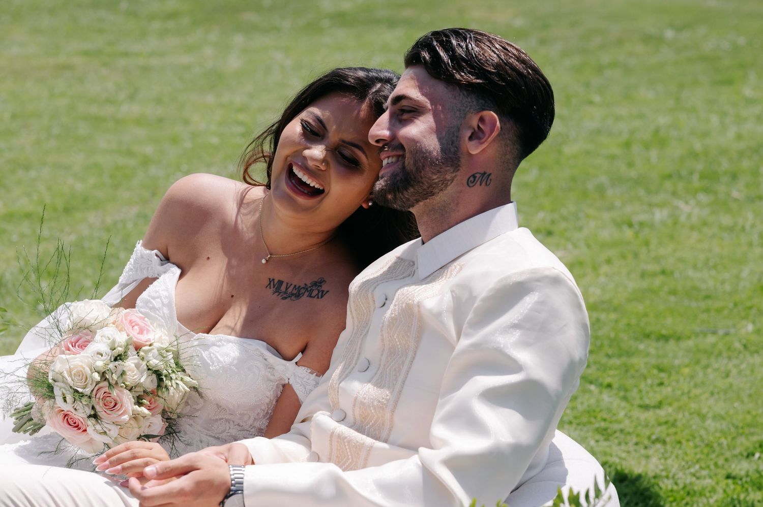 A happy couple shares a joyful moment together outdoors on a sunny day during their wedding celebration.