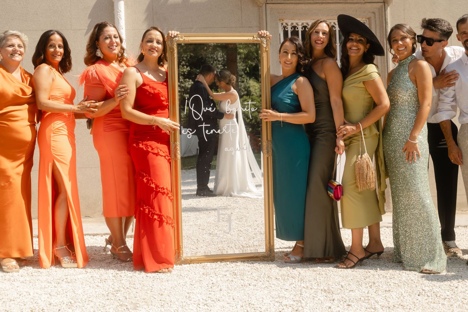 Wedding party members in coral and mint colored dresses lined up at an outdoor venue.