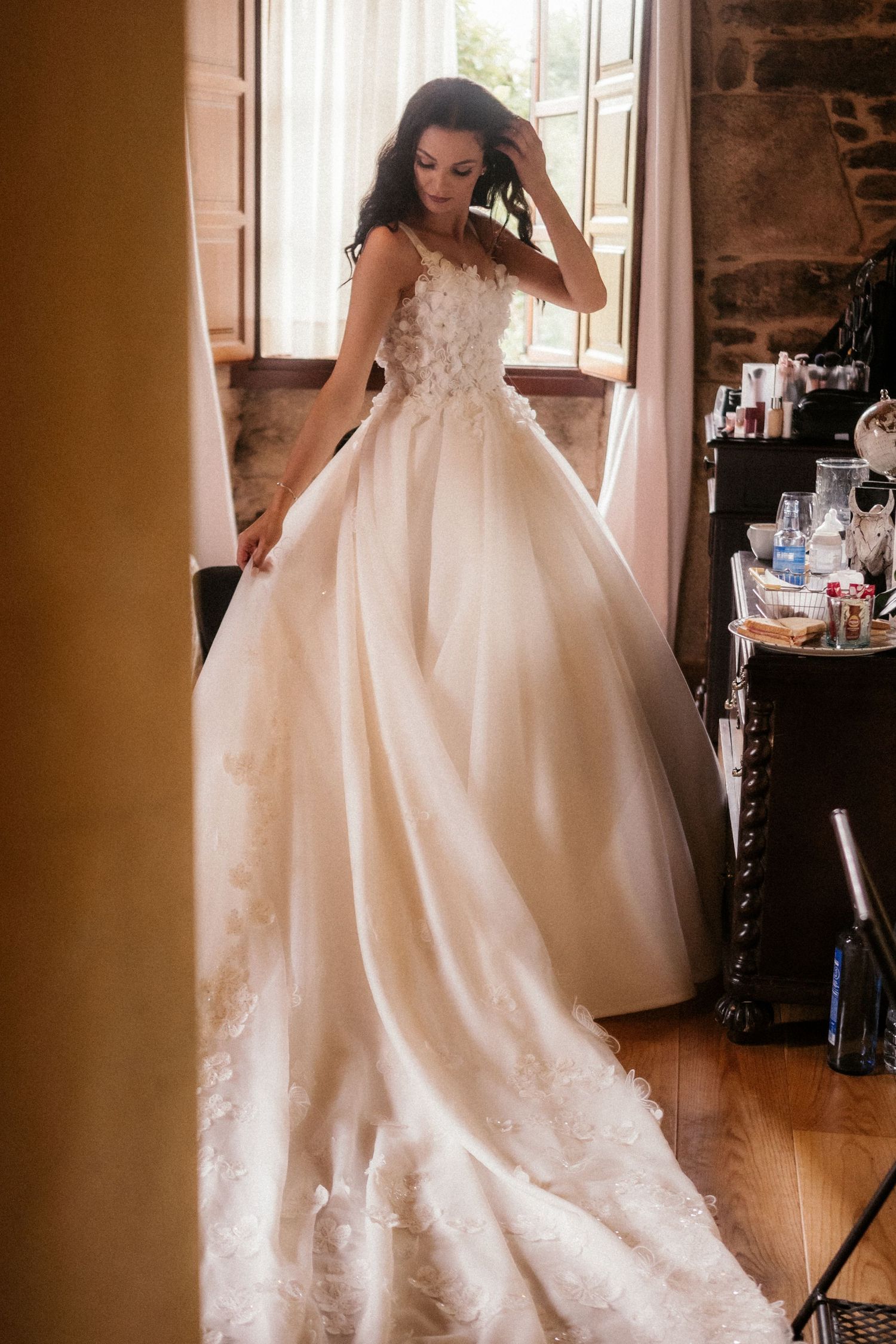 Ethereal white wedding gown with intricate lace details and flowing train captured in warm sunlit room.
