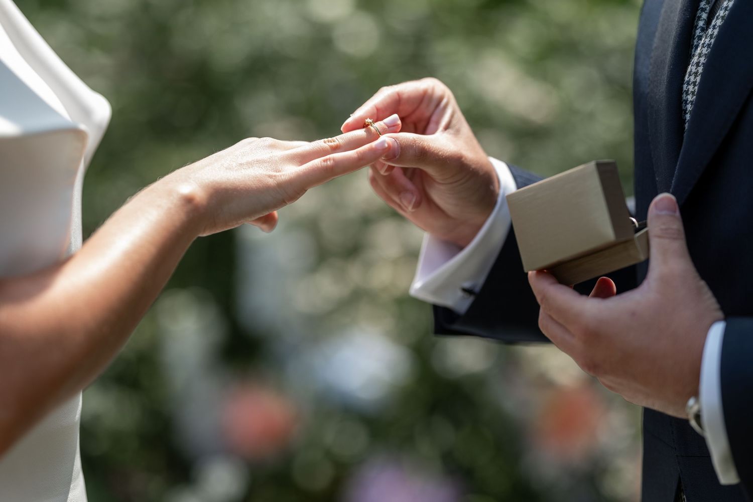 Wedding guests toss white confetti over a couple celebrating their special day outdoors.