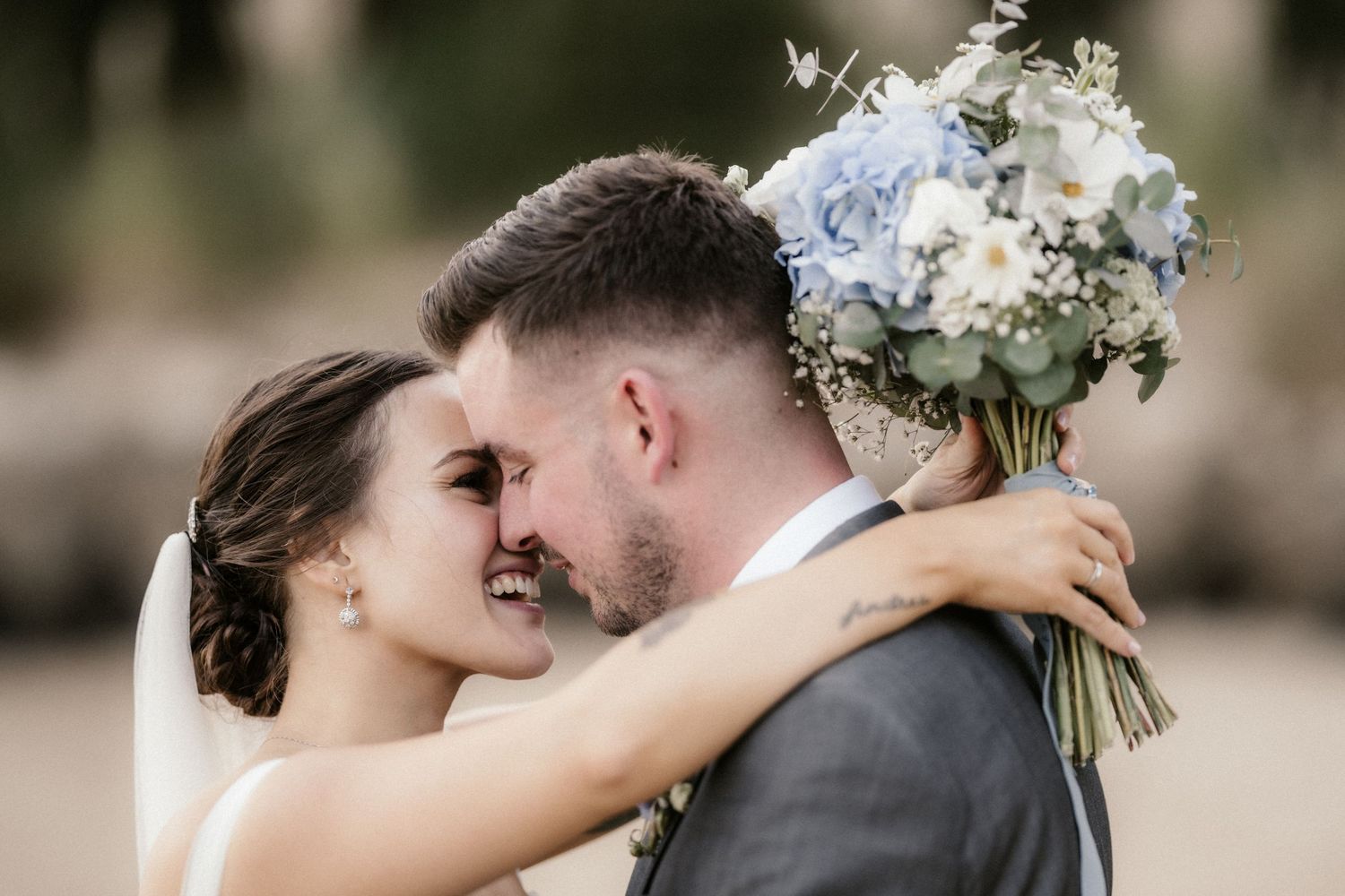 A couple in wedding attire embraces tenderly during their outdoor photo session.