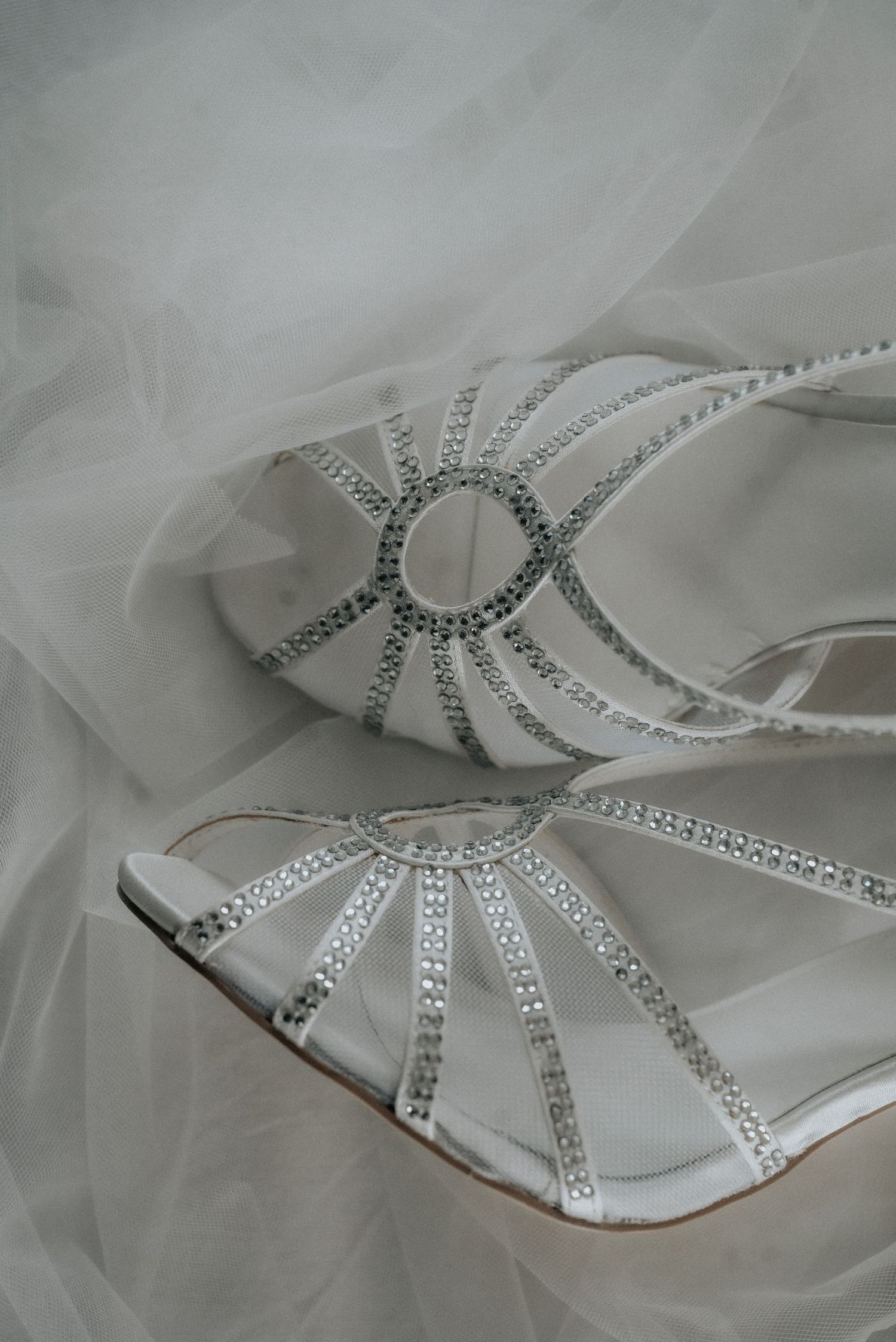 Detailed view of white bridal sandals with crystal embellishments and delicate strap designs.