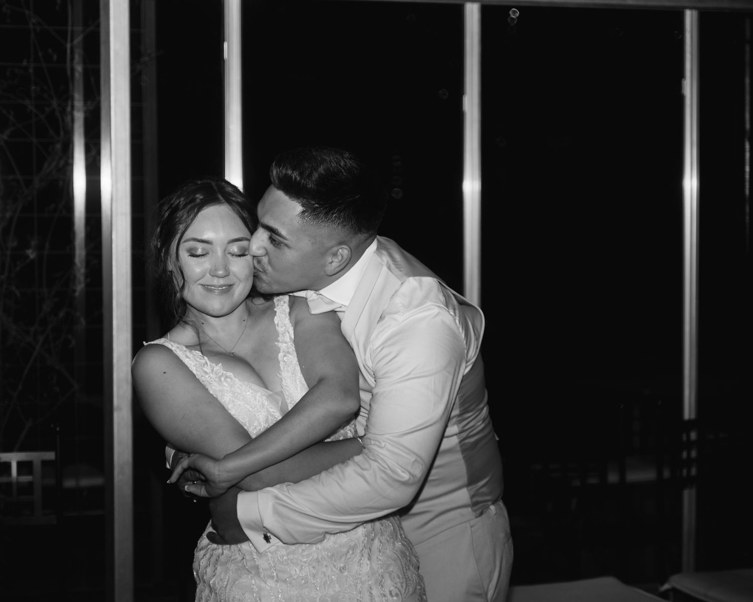 Couple sharing an intimate dance moment in formal attire at a dimly lit venue.
