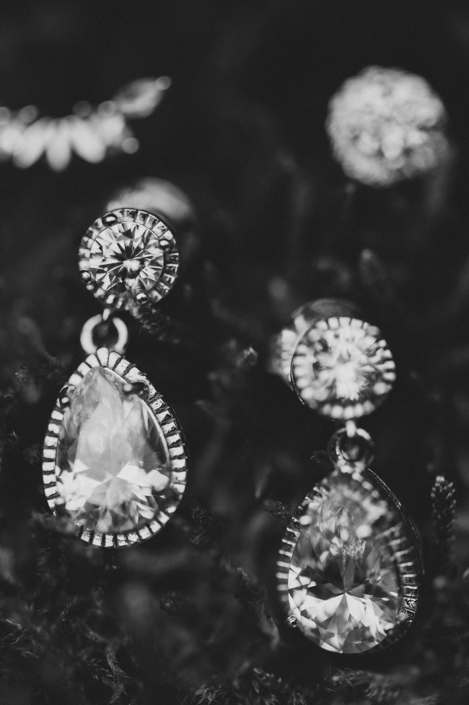 Close-up macro photography of delicate crystal earrings with intricate details in black and white.