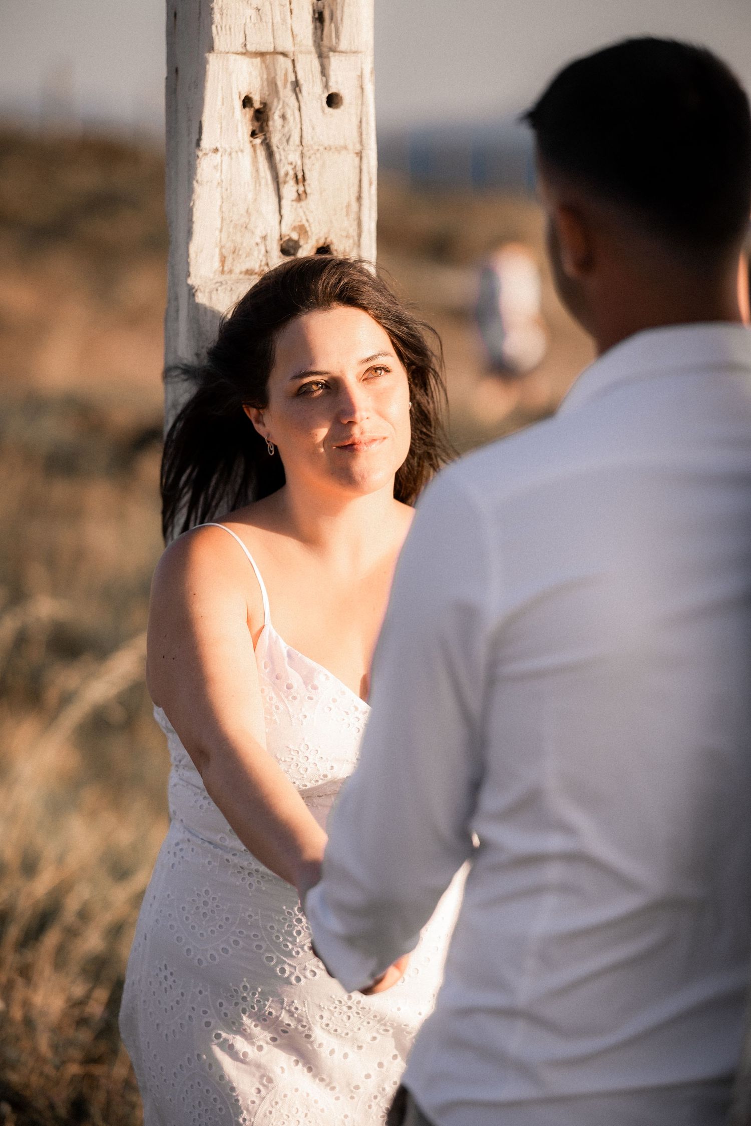 A couple shares a tender moment in a rustic outdoor setting with golden light.