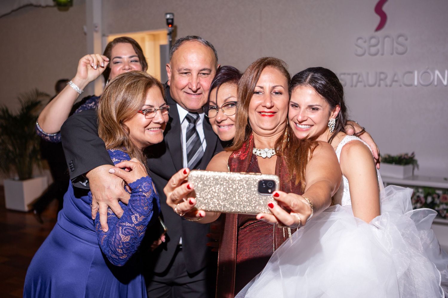 Guests celebrating and dancing together at a lively wedding reception with colorful lighting and decorations.