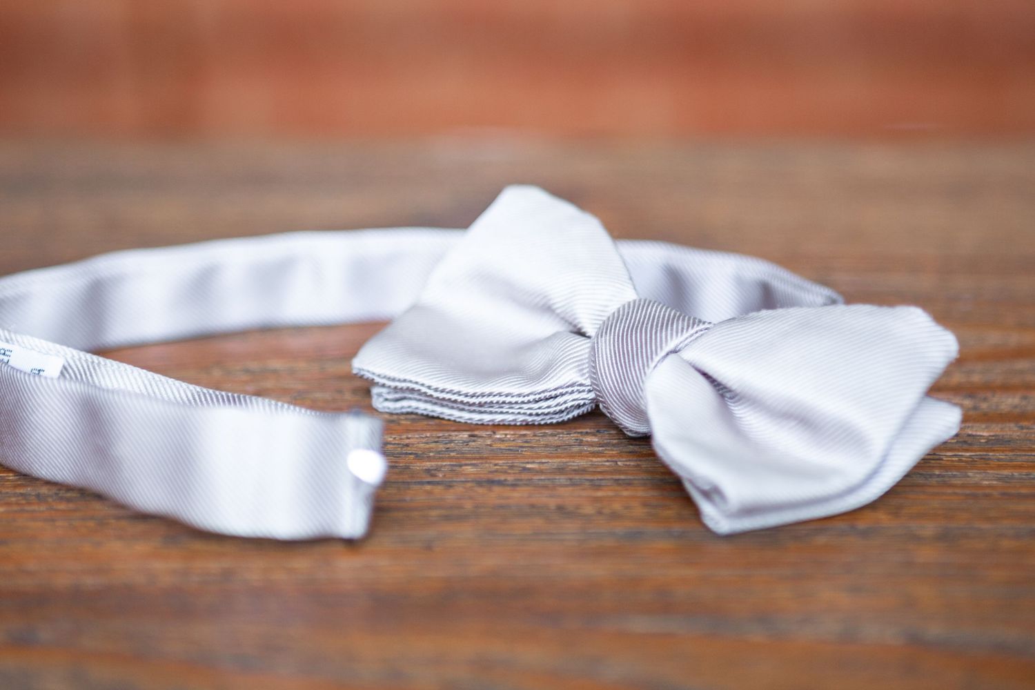 A series of white dryer sheets arranged in a row on a wooden surface shows progressive unfolding stages.