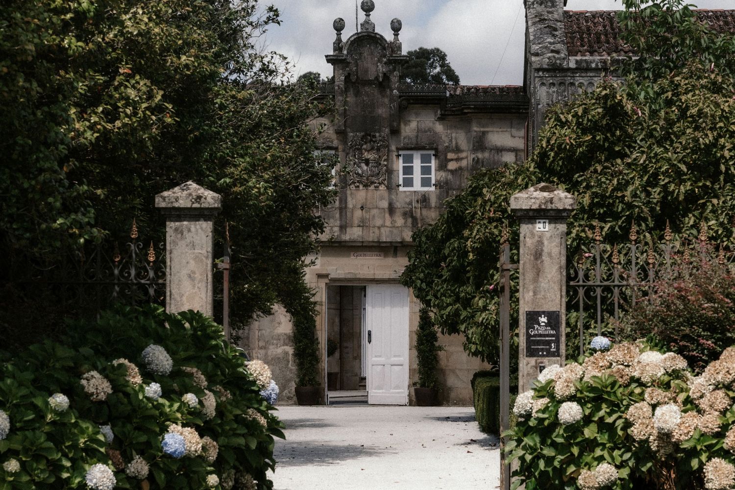 Elegant stone archway entrance to a historic estate with climbing vines and ornate architectural details.